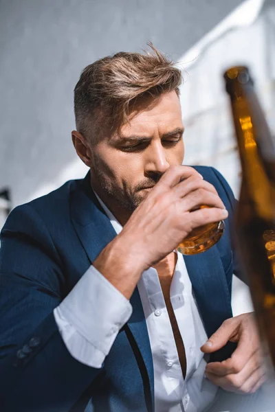 Selective focus of businessman holding glass and drinking whiskey — Stock Photo