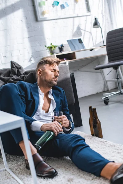 Drunk businessman sitting on carpet with closed eyes — Stock Photo