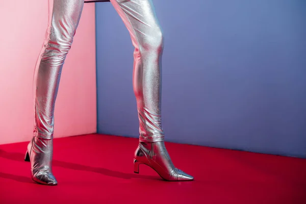 Partial view of fashionable model posing in trendy silver footwear on pink and blue background — Stock Photo