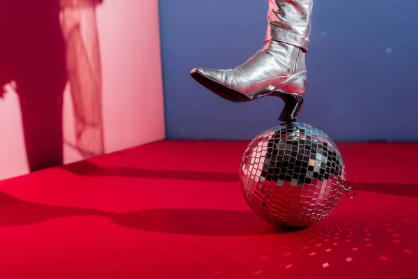 Cropped view of model in metallic footwear posing with disco ball on pink and blue background — Stock Photo