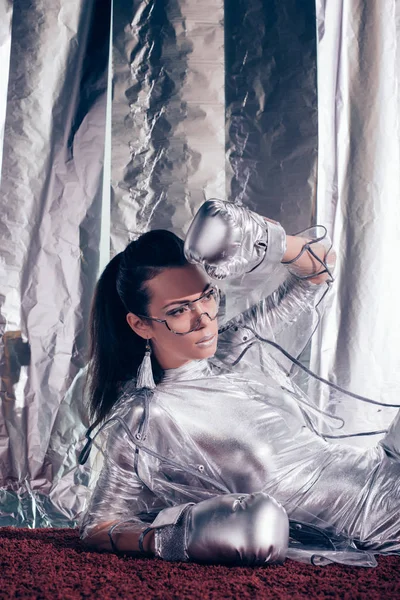 Hermosa chica elegante posando en traje de cuerpo, impermeable y guantes de caja de plata sobre fondo metálico - foto de stock