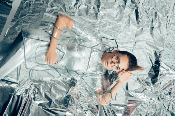 Вид зверху стильна красива дівчина позує в срібному боді і плащі на металевому фоні — Stock Photo