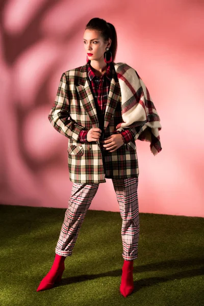 Hermoso modelo posando en traje a cuadros sobre fondo rosa - foto de stock