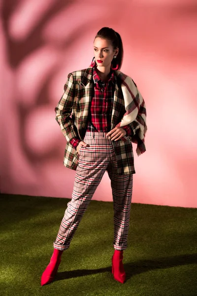 Modello alla moda in posa in tuta a scacchi su sfondo rosa — Foto stock