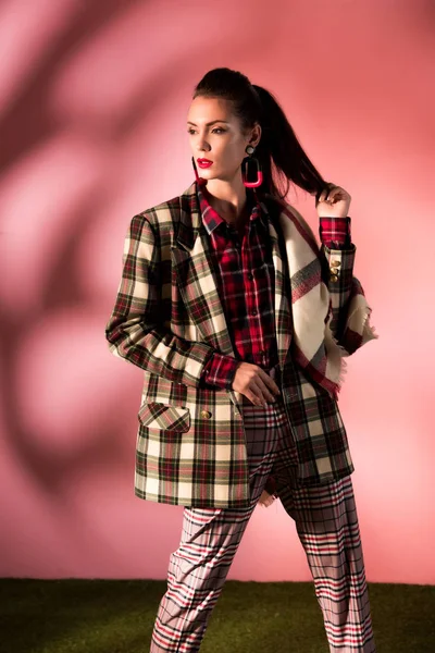 Fashionable girl posing in cozy checkered suit on pink background — Stock Photo