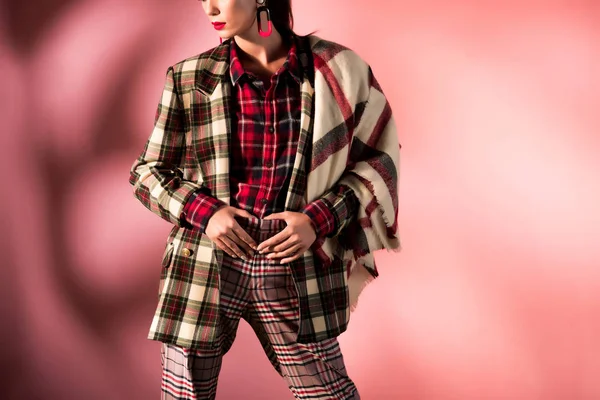 Cropped view of girl posing in warm checkered suit on pink background — Stock Photo