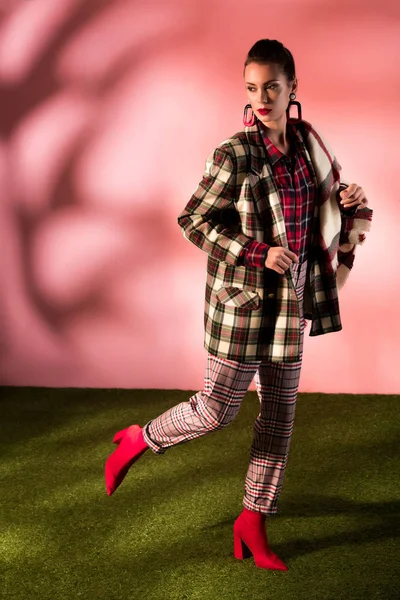 Atractiva joven posando en traje a cuadros sobre fondo rosa - foto de stock