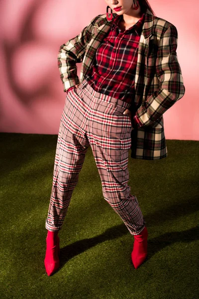 Cropped view of fashionable woman posing in checkered suit on pink background — Stock Photo