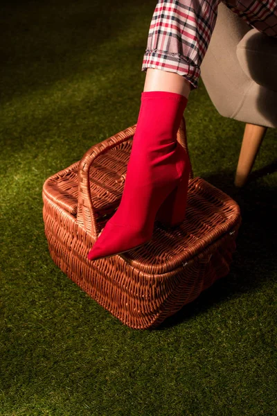 Частичный вид модной женщины в красной обуви, позирующей с корзиной на зеленом ковре — стоковое фото