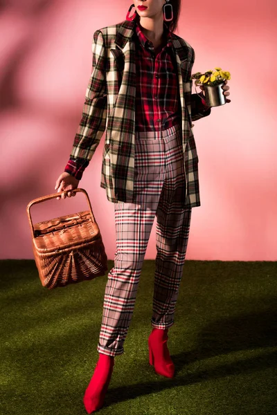 Mulher na moda no outono terno xadrez posando com cesta e flores em rosa — Fotografia de Stock