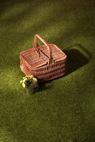 Fiori e cestino di vimini per picnic su erba verde — Foto stock