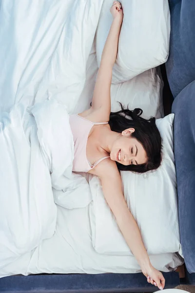 Високий кут зору щасливої дівчини, що тягнеться на ліжко в ранковий час вдома — стокове фото