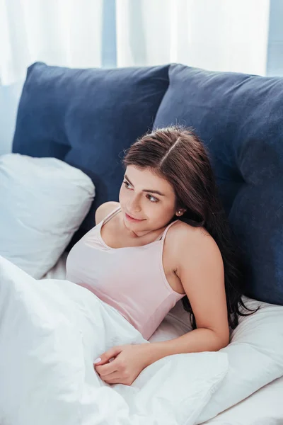 Усміхнена дівчина прокидається на ліжку в ранковий час вдома — стокове фото