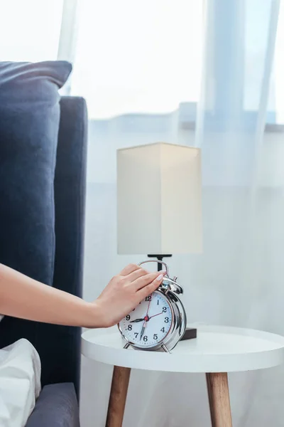 Cropped image of woman turning off alarm clock in bedroom during morning time at home — Stock Photo