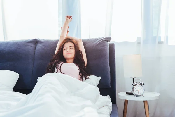 Pretty young woman stretching on bed during morning time at home — Stock Photo
