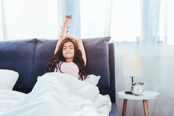 Bella giovane donna che si estende sul letto durante il mattino a casa — Foto stock