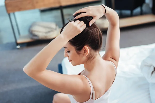 High angle view of girl collecting ponytail while sitting on bed during morning time at home — Stock Photo