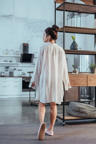 Visão traseira da menina atraente posando em camisa branca durante o tempo da manhã em casa — Fotografia de Stock