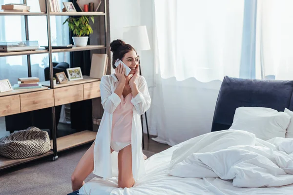 Hermosa joven sonriente mujer hablando en el teléfono inteligente durante la mañana en casa - foto de stock