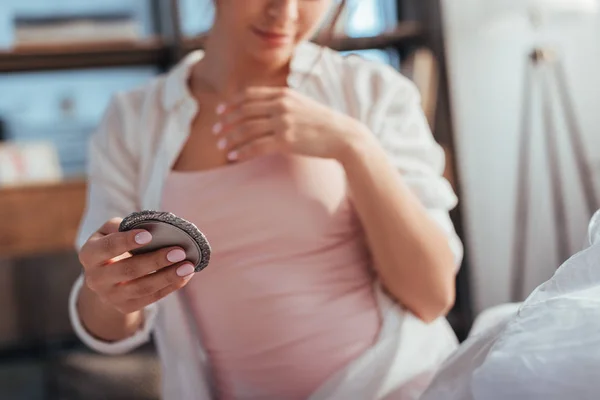 Partial view of girl looking at mirror while sitting on bed at home — Stock Photo