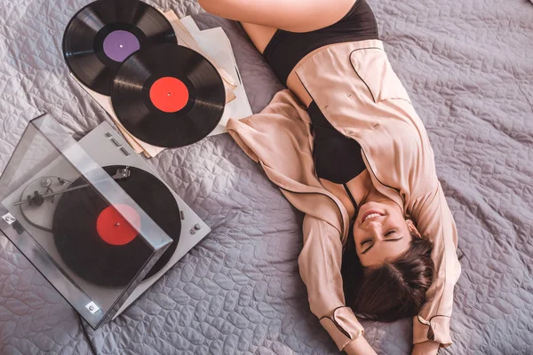 Blick aus der Vogelperspektive auf Mädchen, die auf dem Bett liegen und zu Hause Vinyl-Audio-Player hören — Stockfoto