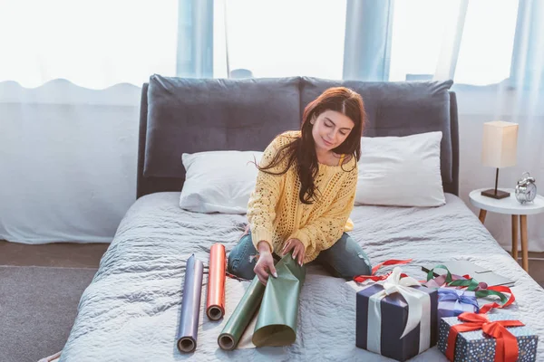 Enfoque selectivo de hermosa mujer joven embalaje regalo mientras está sentado en la cama en casa — Stock Photo