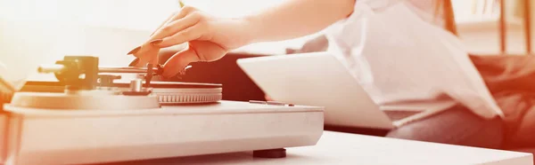 Cropped view of woman with laptop playing vinyl record — Stock Photo