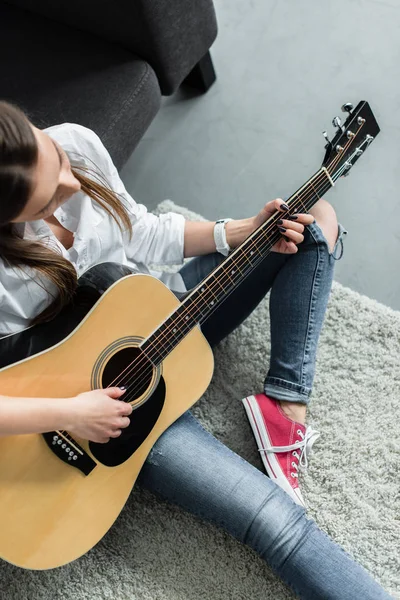 Teilansicht eines Mädchens, das im Wohnzimmer sitzt und Gitarre spielt — Stockfoto