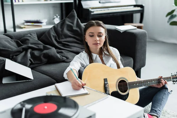 Foco seletivo de menina com escrita de guitarra acústica em notebook ao compor música em casa — Fotografia de Stock