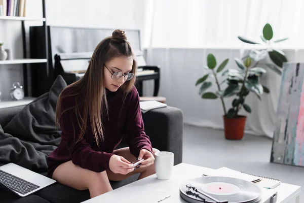 Fille assise à table et rouler joint de marijuana dans le salon — Photo de stock