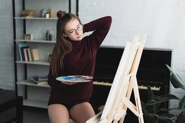 Attraente ragazza in maglione bordeaux seduta e pittura a casa — Foto stock