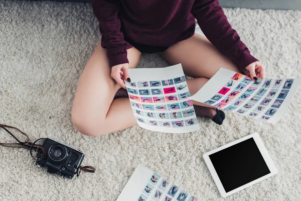Обрізаний вид фотографа, що сидить на килимі і тримає фотографії — Stock Photo