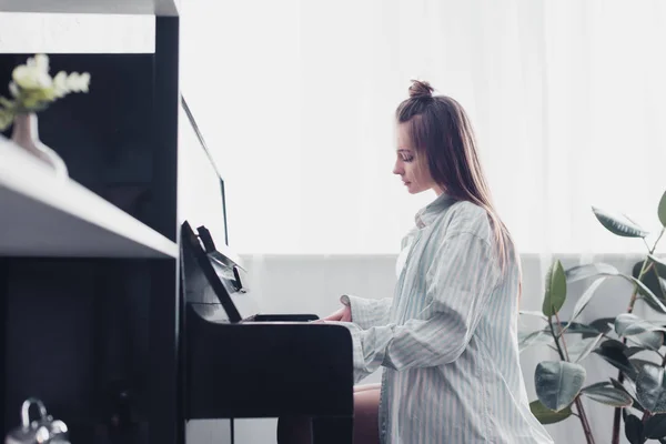 Вид збоку привабливого музиканта, який грає на піаніно у вітальні — стокове фото