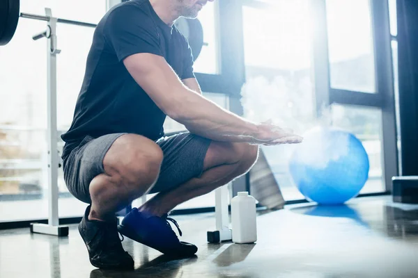 Immagine ritagliata dello sportivo che applica talco in polvere sulle mani che esercitano l'allenamento in palestra — Foto stock