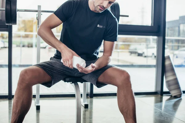 Imagen recortada de hombre atlético aplicando talco en las manos antes de entrenar en el gimnasio - foto de stock