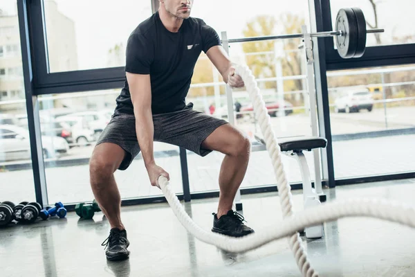 Обрезанный образ спортсмена, тренирующегося с веревками в тренажерном зале — стоковое фото