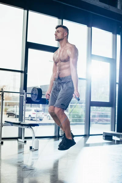Красивый спортсмен без рубашки упражняется с скакалкой в спортзале — стоковое фото