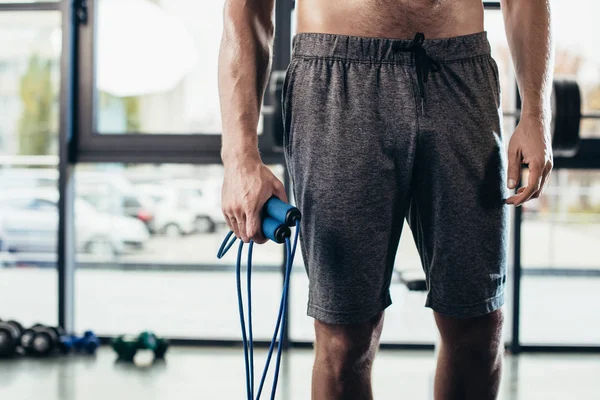 Mid section of shirtless sportsman holding jumping rope in gym — Stock Photo
