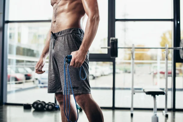 Mid section of shirtless sportsman holding skipping rope in gym — Stock Photo