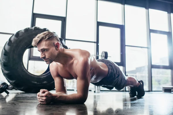 Schöner hemdloser Sportler beim Planken im Fitnessstudio — Stockfoto