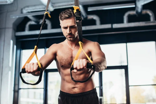 Apuesto deportista deportivo de entrenamiento con bandas de resistencia en el gimnasio - foto de stock