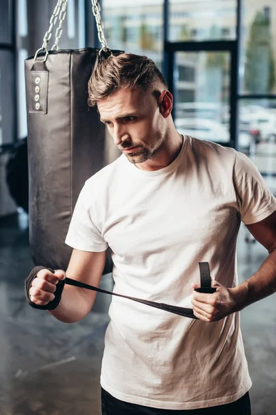 Handsome sportsman wearing sports bandage in gym — Stock Photo