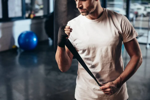 Cropped image of sportsman wearing sports bandage in gym — Stock Photo