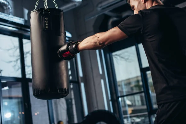 Side view of handsome boxer training with punching bag in gym — Stock Photo