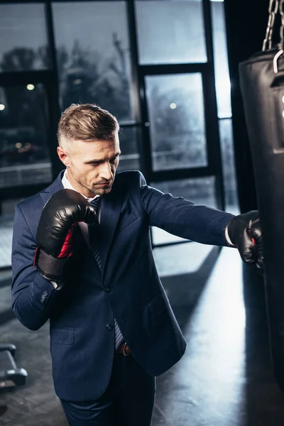 Bel homme d'affaires en costume boxe dans la salle de gym — Photo de stock