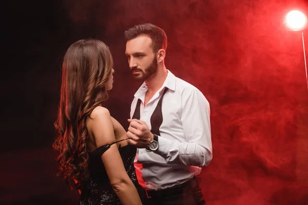 Seductive young couple in red smoky room — Stock Photo