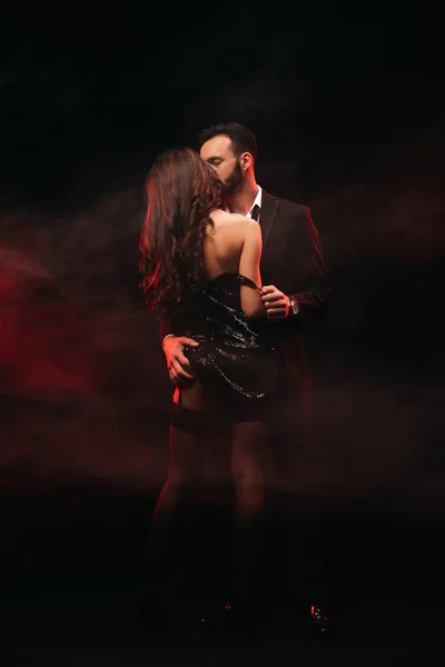 Attractive passionate couple hugging in red smoky room — Stock Photo