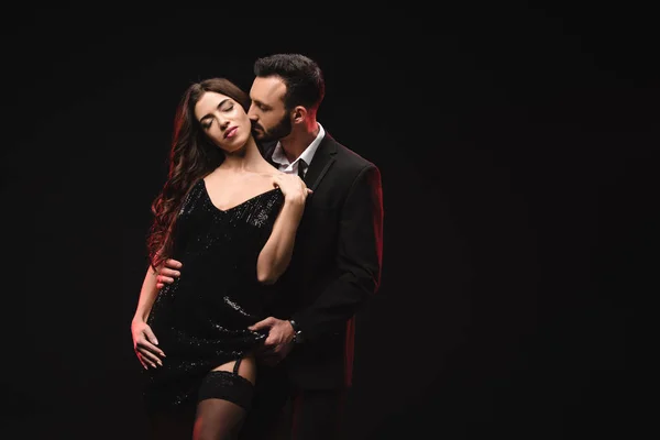 Attraktives Liebespaar in schwarzem Kleid und Smoking isoliert auf schwarz — Stockfoto