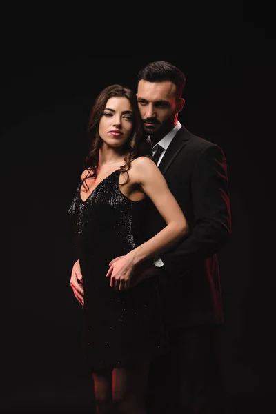 Hermosa pareja en vestido negro y esmoquin aislado en negro - foto de stock