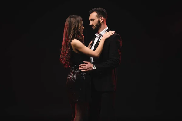 Sexy casal no preto vestido e smoking abraço isolado no preto — Fotografia de Stock